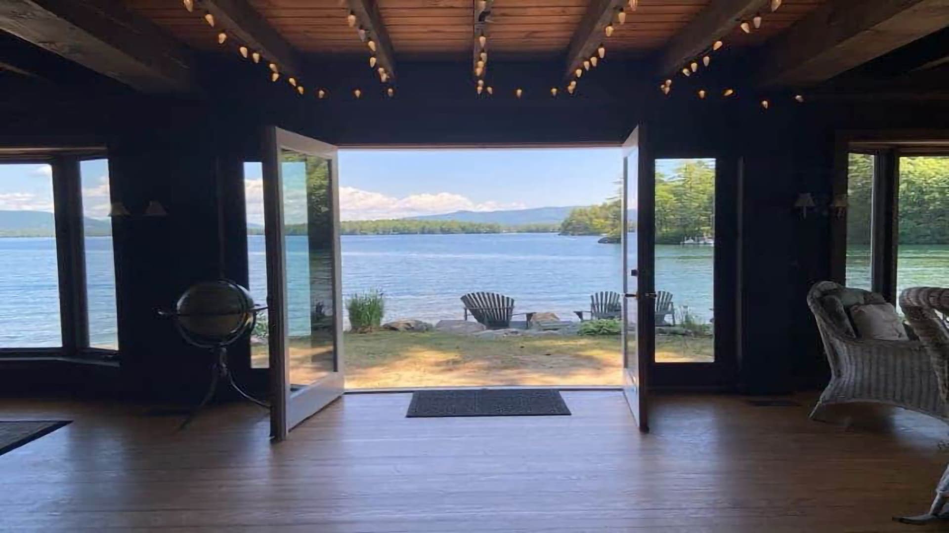 View of a serene lake through open double doors, framed by rustic interior decor.